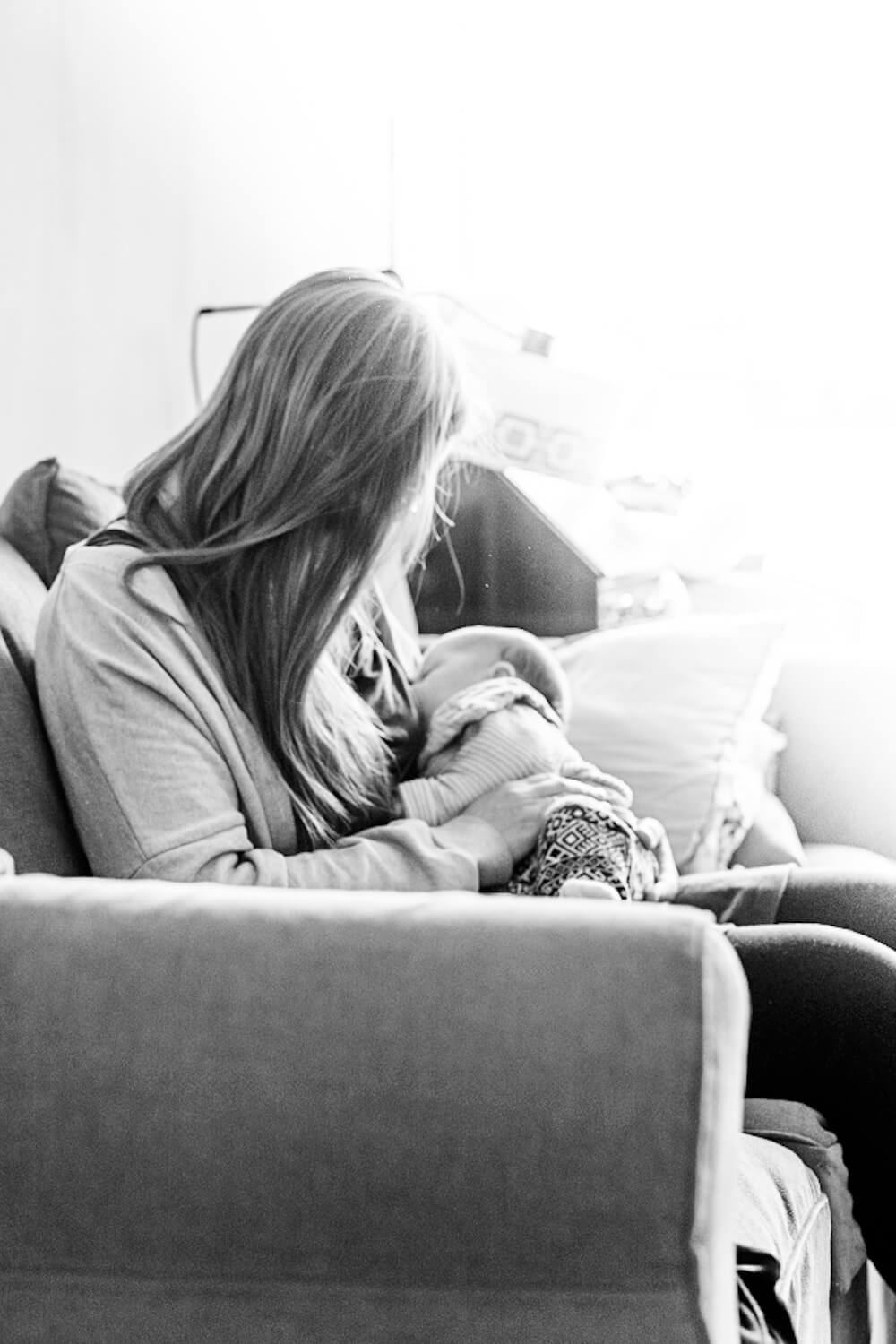 Ein Foto von einem Neugeborenenshooting. Die Mutter still das Baby. Es ist ein schwarz/weiß-Foto.
